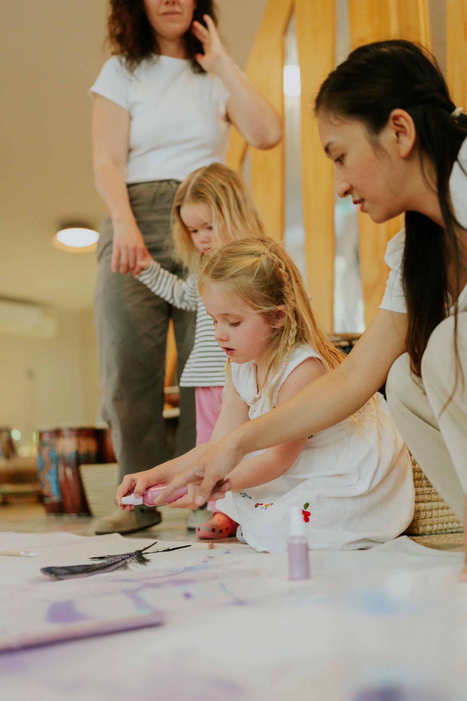 Children paint on the floor with two educators
