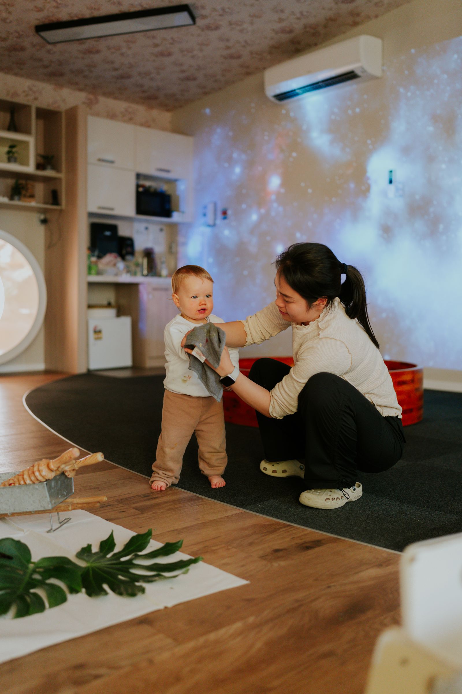 An educator kneels with a toddler at floor level