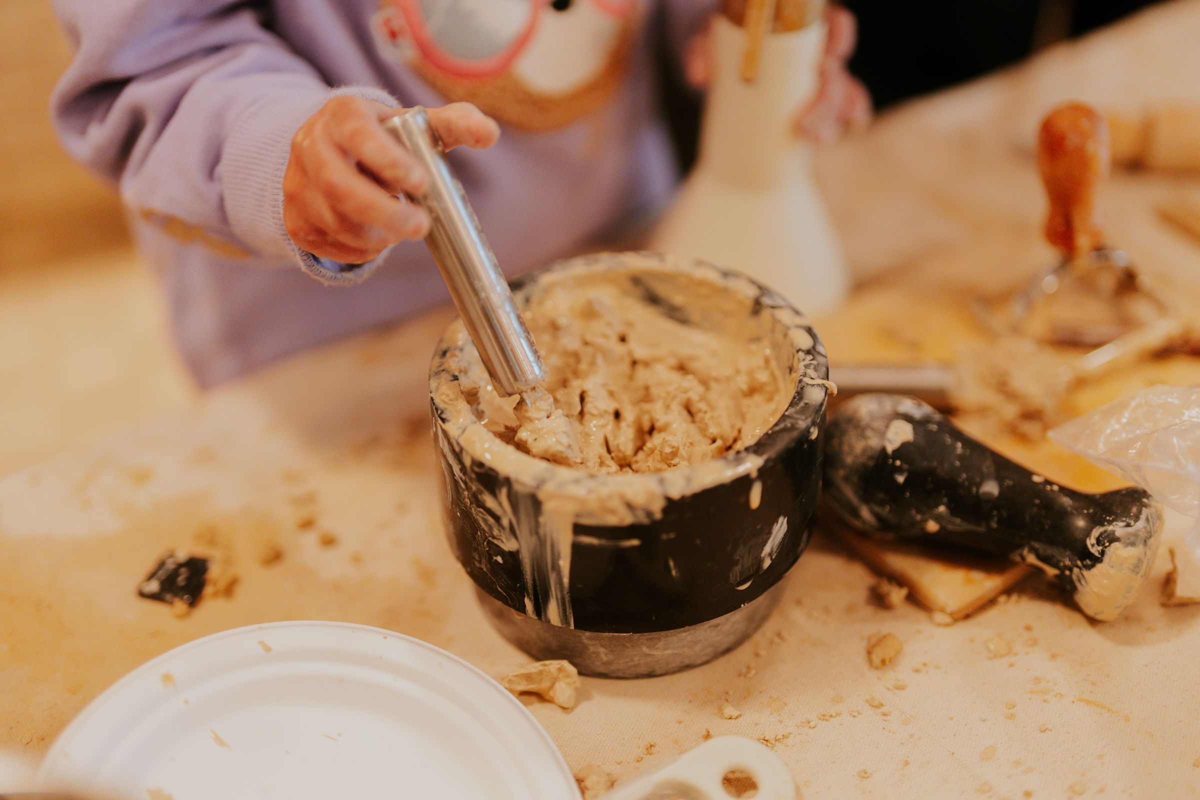 Hands mixing a clay mixture in a pot