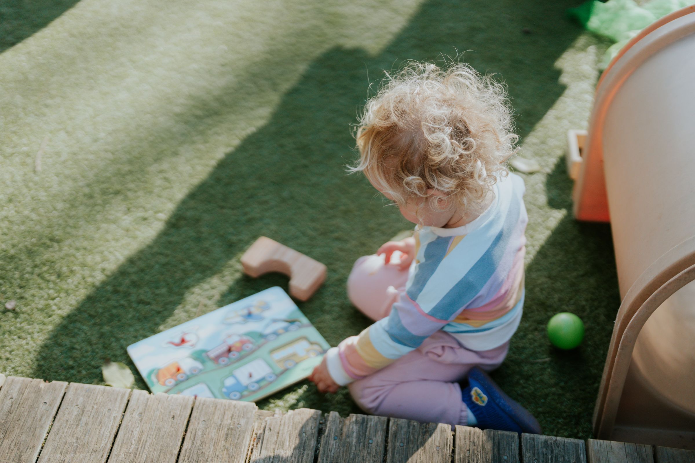 A toddler plays on the grass in the garden